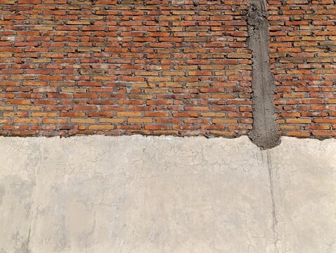 A half-finished brick wall meets a rough concrete section. The contrasting textures show ongoing construction.