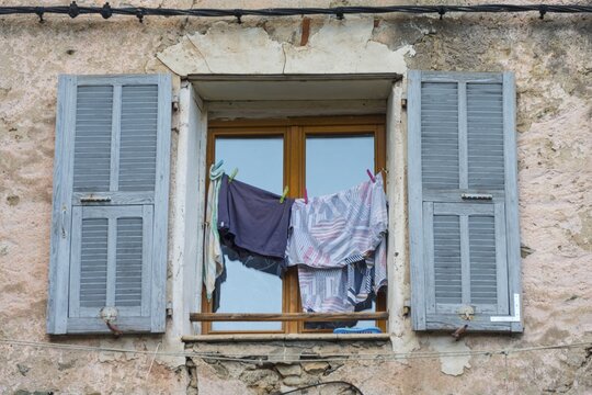 Window in a dilapidated building with laundry  and open shutters, Corte, Corsica, France