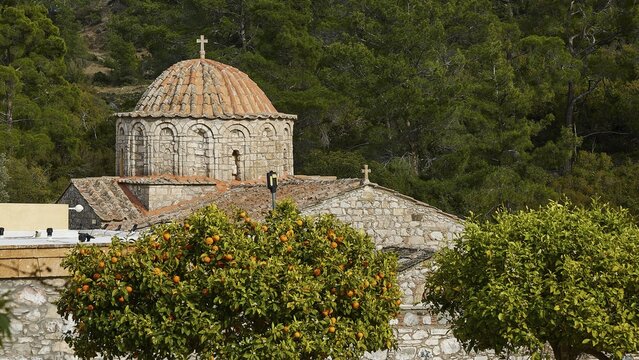 Stone church with dome in the background framed by orange trees, monastery, Moni Thari, near Gadouras reservoir, lonely mountain region, Rhodes, Dodecanese, Greek Islands, Greece