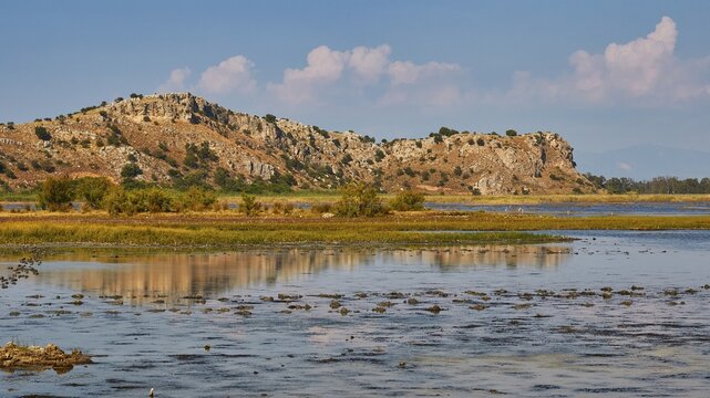 Wetland with a view of rocky hills and scattered clouds in the sky, Strofilia biotope, wetlands, Kalogria, Peloponnese, Greece