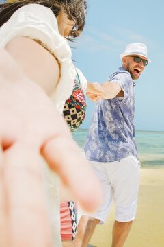 Cheerful young man leading woman couple holding hands run to beach have fun together on shallow turquoise ocean water sandy beach tropical island resort destination. Relationship honeymoon vacation.Zanzibar