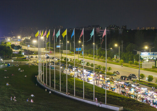 Night street market beside grassy park and flag avenue in the city