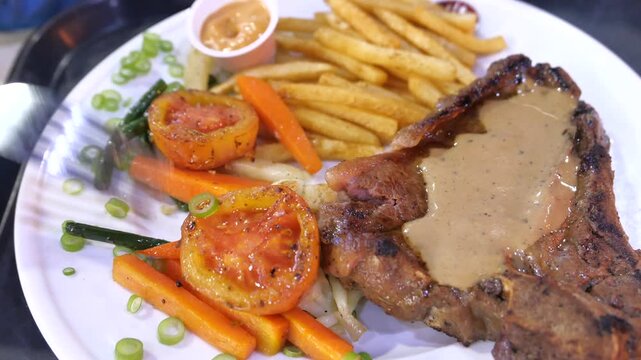 Close up on delicious steak dinner with french fries and vegetables being served