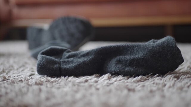 Close up slow motion video of black socks on a light colored carpet floor, illustrating domestic scene and everyday clothing