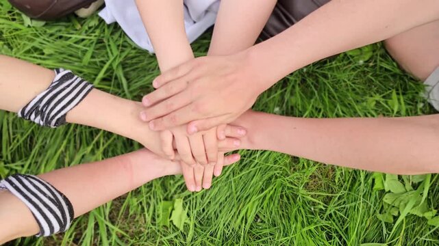 Hands gathering on grass during a group activity on a warm day