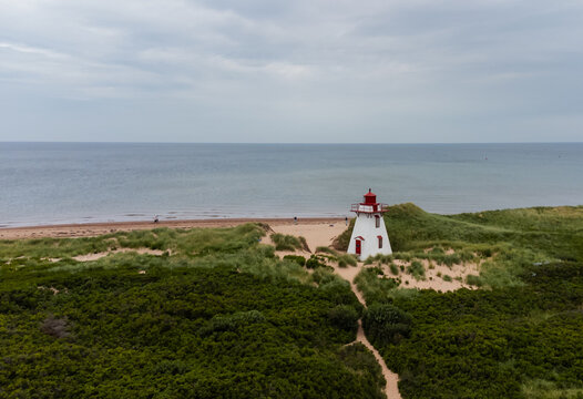Wooden red and white lighthouse on a grassy dune by the ocean