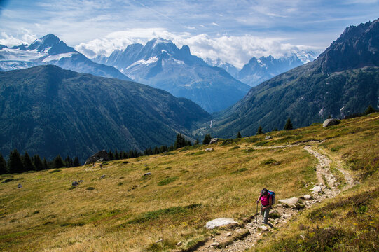 Hiker on a trail in the mountains during daytime with clear skies and
