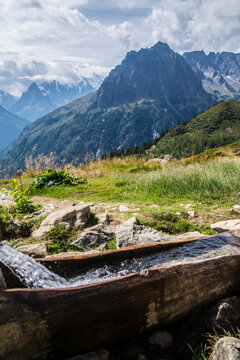 Fresh spring water flowing into a wooden trough in the Alps