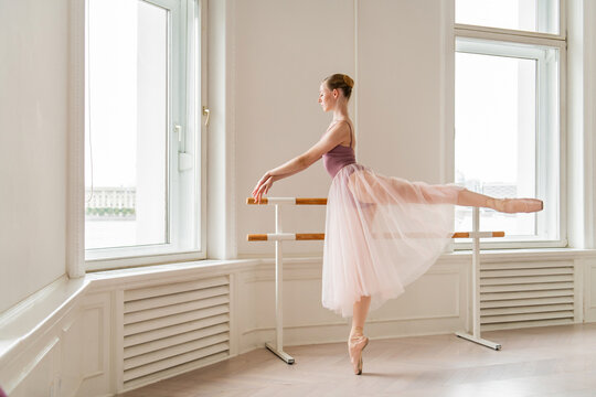 Graceful ballerina practices an arabesque at the barre