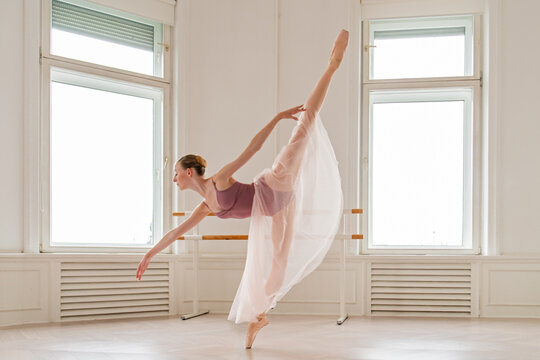 Graceful ballerina performing a standing split in studio