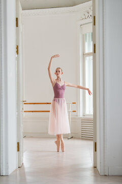 Young ballerina performs en pointe in a white dance studio
