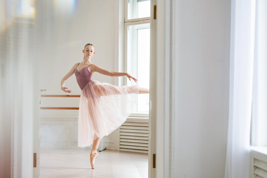 Graceful ballerina practices an arabesque in a dance studio