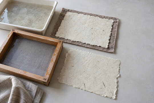 Handmade paper sheets and a wooden papermaking screen