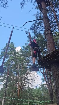 Person swings on a rope from a platform in the trees during an afternoon in a forest park