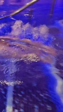 People enjoy aqua therapy in a blue tiled pool during night hours at a wellness center