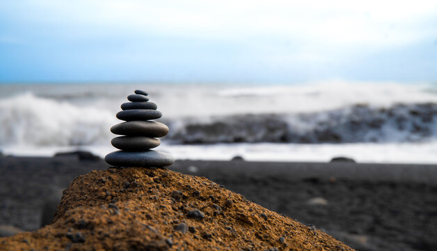 Balanced Zen Stones Pyramid on Rock with Ocean Waves Background in Iceland
