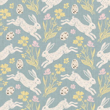 Seamless Easter pattern featuring hand drawn jumping rabbits with speckled eggs and spring flowers on a soft blue linen texture background for festive holiday textile design projects