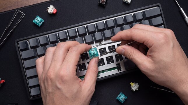 Hands using a puller tool to replace a switch on a hot-swappable keyboard