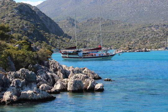 demre, Turkey - White and Maroon Sailing Gulet Anchored in Turquoise Bay with Rocky Hills