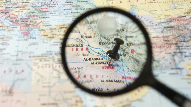 Magnifying glass highlights Kuwait on printed map