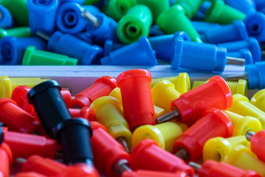 Assorted colorful plastic threaded fasteners metal screws red yellow blue green black representing industrial hardware components assembly manufacturing