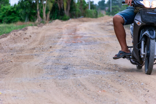 Motorcycle rider traveling an uneven rural dirt road gravel dust representing countryside transportation road conditions mobility infrastructure