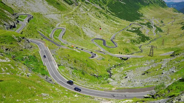 Hairpin bends of the Transfagarasan road crossing a green valley in the Romanian Carpathian Mountains