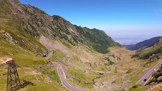 Panoramic view of the winding Transfagarasan road across steep green slopes in the Romanian Carpathians