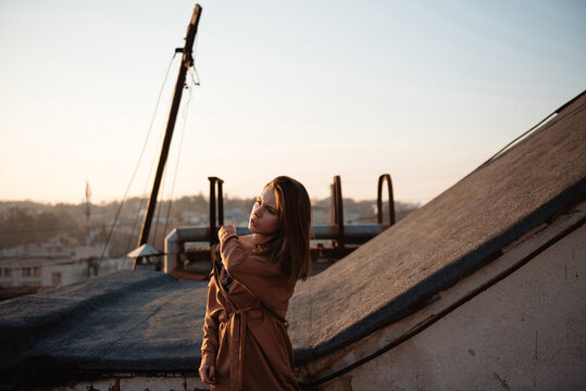 Young woman posing on a rooftop during a golden hour autumn sunset