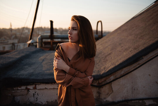 Young woman embracing herself on a rooftop during a golden hour sunset