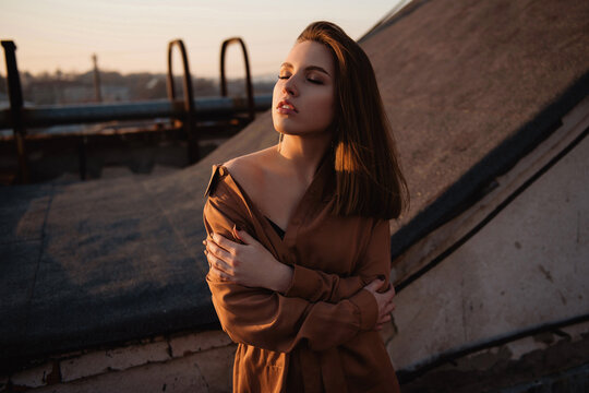Woman embracing herself on rooftop during golden hour sunset