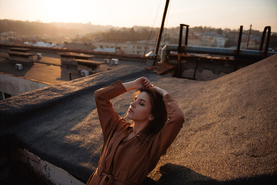 Woman enjoying golden hour sunset on a rooftop overlooking city buildings