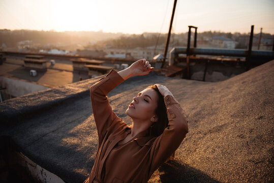 Woman enjoying golden hour sunset on a rooftop with city view