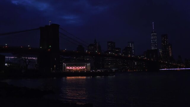 Brooklyn bridge at night with new york city skyline and illuminated stage.