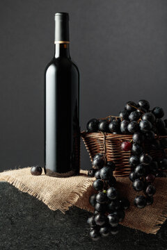 Juicy blue grapes and a bottle of red wine.
