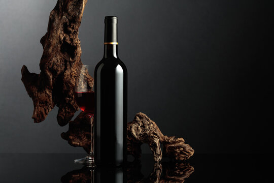 Red wine and old snag on a black background.