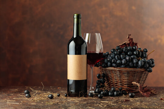 Bottle of red wine and blue grapes in old basket.