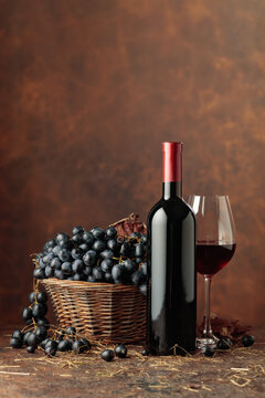 Bottle of red wine and blue grapes in old basket.