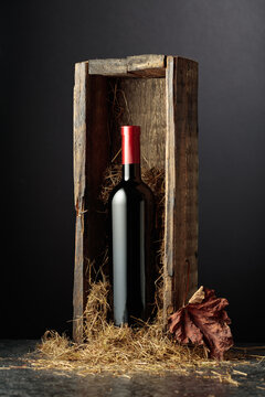 Bottle of red wine in old wooden box on a black background.