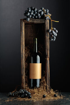 Bottle of red wine in old wooden box on a black background.