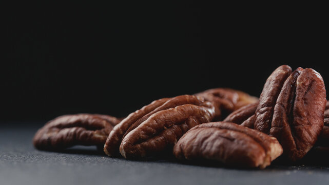 Macro shot of fresh premium pecan nuts with selective focus, on dark background with artistic lighting. Perfect for healthy eating, gourmet food, culinary, and dietary content.