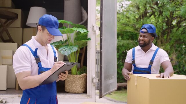 Home moving and delivery service concept. Teamwork of professional home and furniture moving with a truck from business service company. Two male movers in uniforms working and delivering to customer.