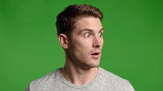 Young man making surprised expressions on green screen background
