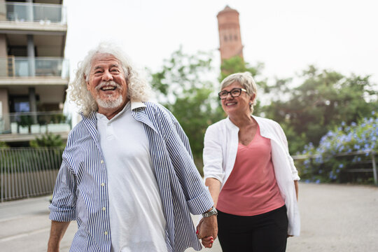 Senior couple walking in urban park talking together and enjoying peaceful retirement lifestyle