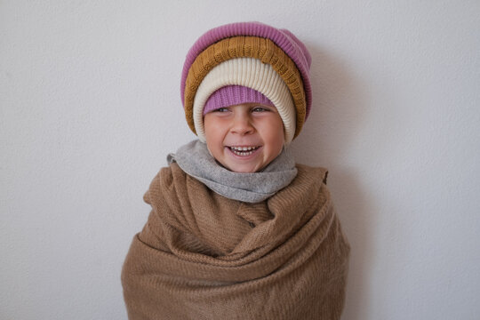  girl wrapped in warm scarf wearing several knitted winter beanies