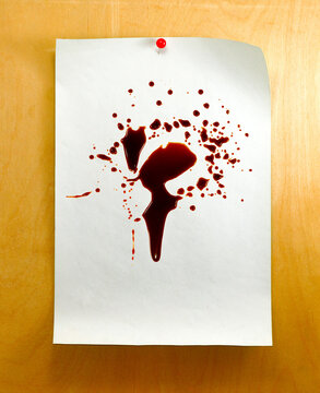 Red liquid splatter is seen on white paper pinned to wooden surface