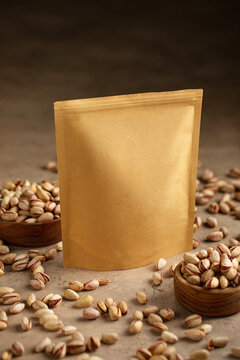 Blank craft paper zipper pouch packaging mockup surrounded by roasted salted pistachios on stone background