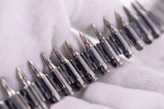 A close-up photo of a silver bracelet designed to look like a machine-gun belt. Rifle Bullet Ammunition Belt Close Up in hand wearing white textile glove