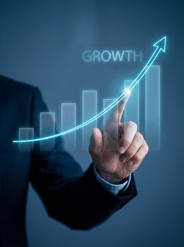 Businessman pointing at a glowing digital growth chart with an upward arrow