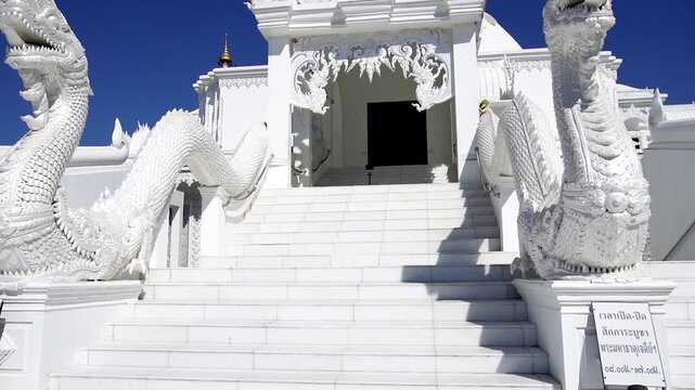 AYUTTHAYA, THAILAND - SEPTEMBER 12, 2026: Sacred Buddhist architecture features a white stupa pagoda and revered monk wax statues inside temple grounds at Ayutthaya province.